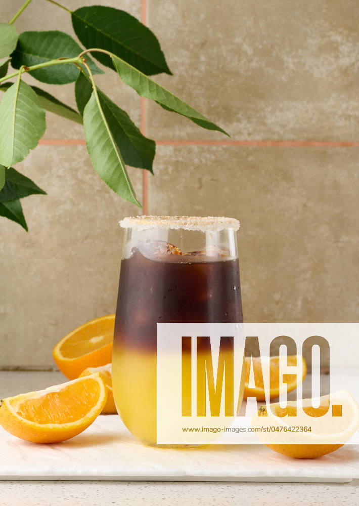 Cold coffee with orange juice in a transparent glass and orange slices