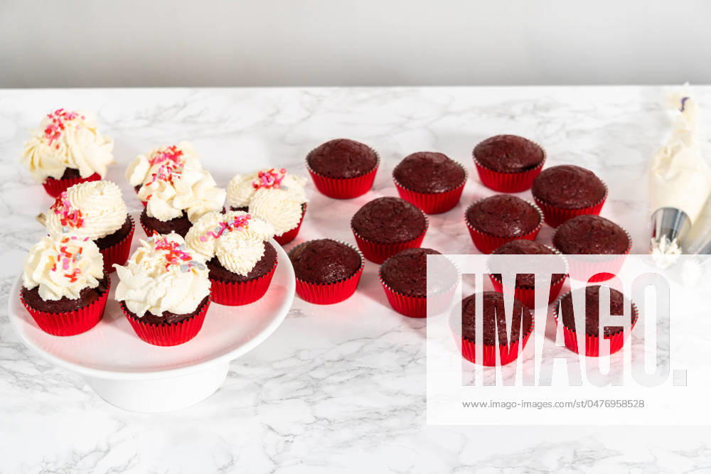 White chocolate ganache frosting Piping white chocolate ganache frosting on top of red velvet cupcakes and topping with sprinkles.