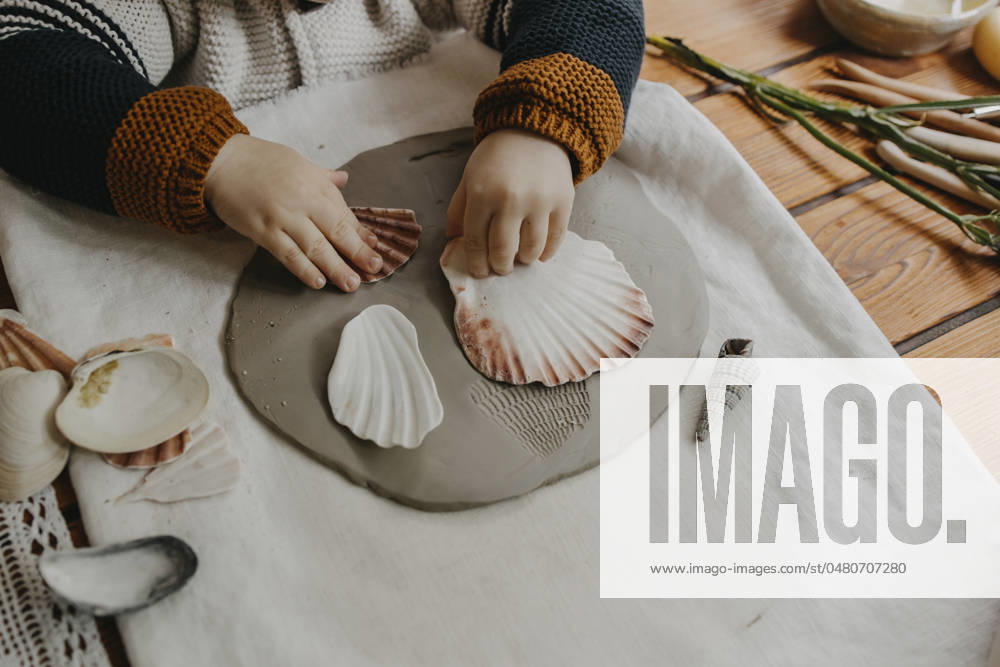 Boy making seashell imprint on clay at home model released, Symbolfoto property released, MCHF00100