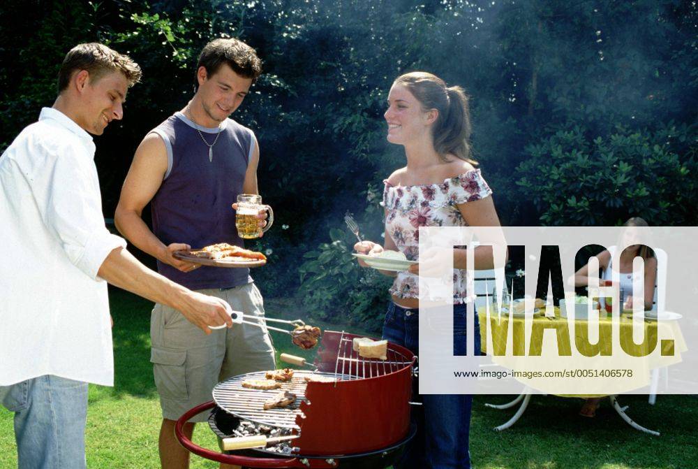Grillparty im Sommer - Zwei junge Männer und eine Frau stehen um einen Grill