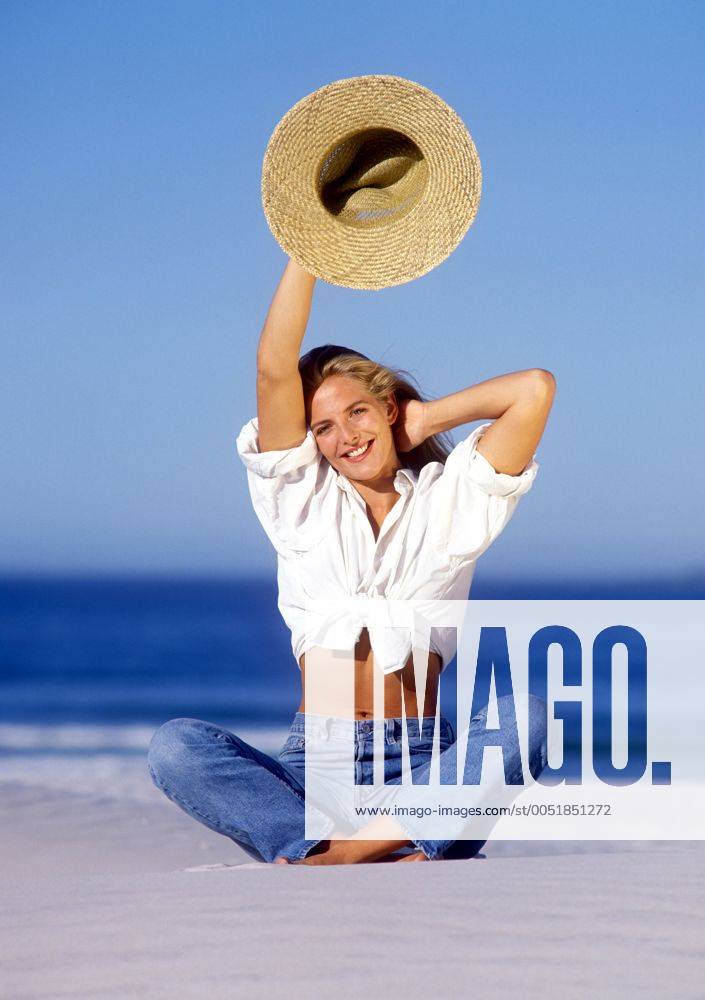 Junge Frau mit Sonnenhut an einem Sandstrand