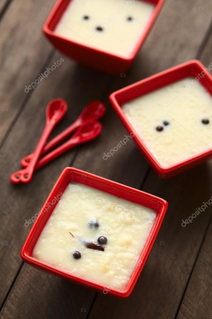 Three red bowls of the Ecuadorian dessert called morocho (coarsely ground white corn) cooked with milk, sugar and spices (cinnamon and allspice), similarly to rice pudding (Selective Focus, Focus into the middle of the lower bowl)