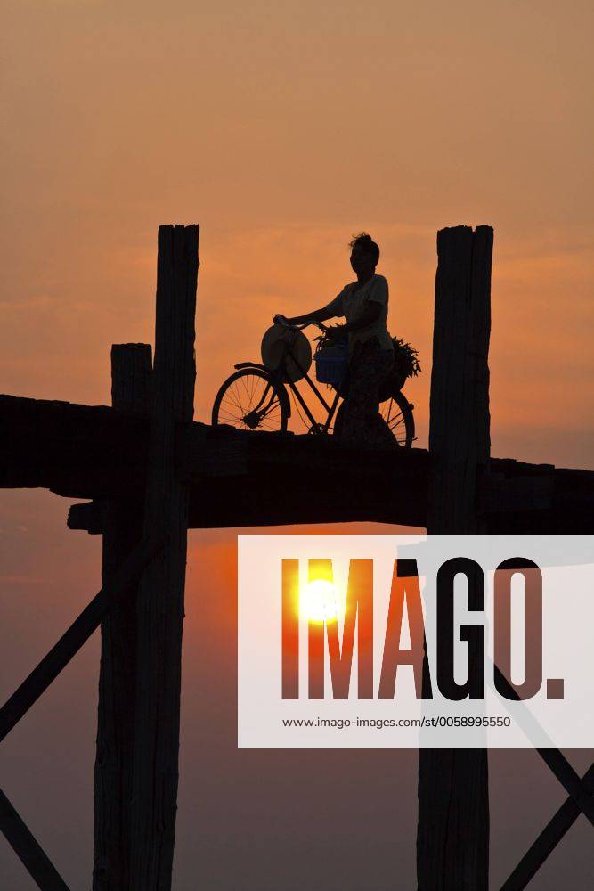 Frau schiebt ihr Fahrrad ueber die U-Bein-Bruecke ueber den Taungthaman-See bei Sonnenaufgang, Myanmar, Amarapura The BURMESE use the teak U BEIN BRIDGE to commute across the Taungthaman Lake at sunrise , Burma, Amarapura BLWS323196