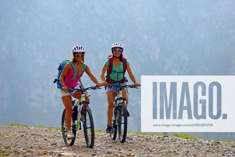 Zwei junge Frauen mit Mountainbikes auf einem Schotterweg im Gebirge, Frankreich, Savoie, Vanoise Nationalpark, Champagny two female mountain bikers on gravel path in the Alps, France, Savoie, Vanoise National Park, Champagny BLWS369184