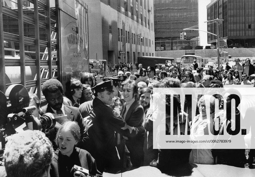 New York, New York: May 12, 1972 John Lennon and Yoko Ono get an assist from a policeman as they try to work their way through the crowd after leaving the Immigration Office on Broadway. 990_16_X-Beatles_2HR