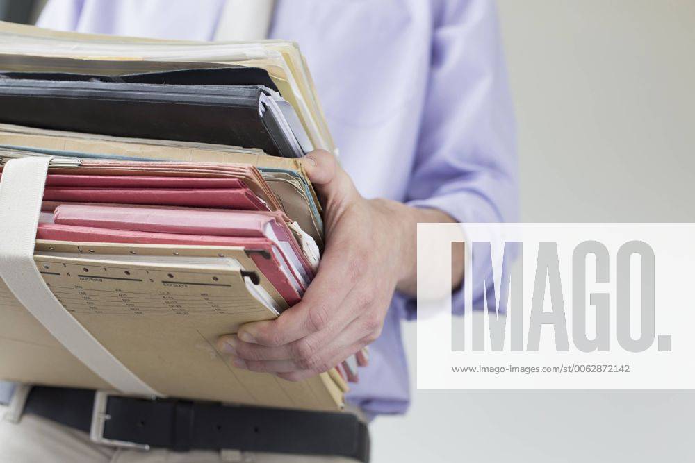 Businessman holding stack of files in office, close up mit_2002_01585