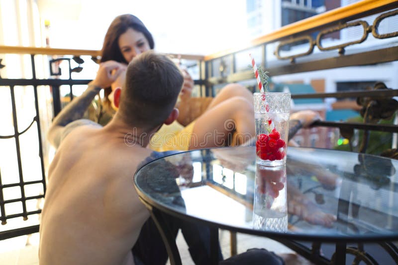 Couple in love drinking summer refreshing lemonade with rasberry on a balcony, Happy couple in love drinking summer refreshing lemonade with rasberry on a balcony