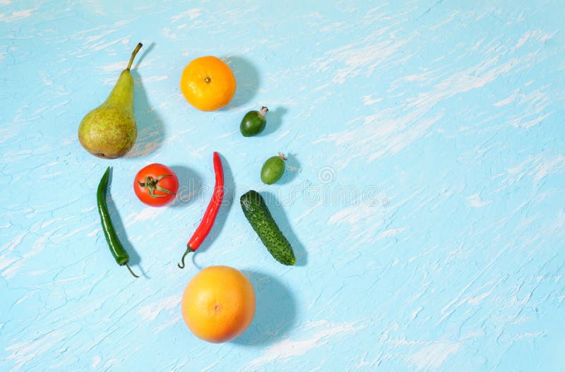 Vegan food. Healthy diet concept. Fruits, vegetables, blue background, a flatlay, Fresh vegetables and fruits cucumber tomato chili pepper tangerine feijoa pear. on a blue background top view