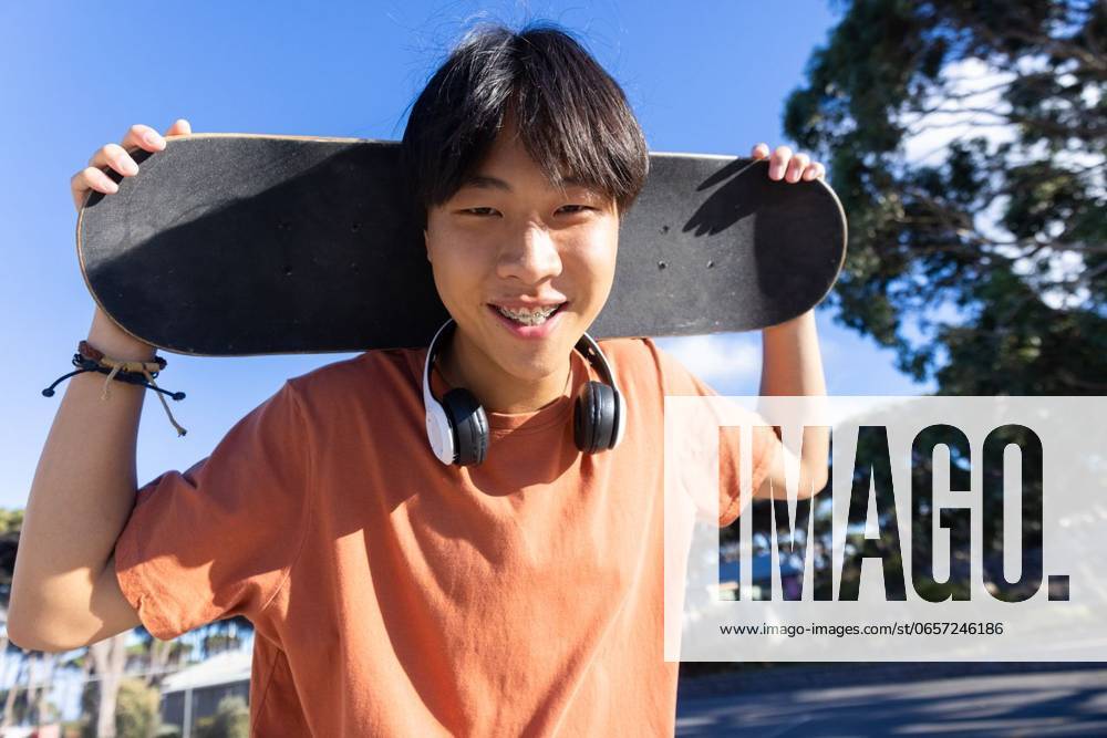 IMAGO Creative: Sommer, Sommertage im Stadtpark Holding skateboard and wearing headphones, teenage boy smiling outdoors Holding skateboard and wearing headphones, teenage boy smiling outdoors. Youth, lifestyle, urban, leisure, music, trendy, unaltered, model released, , property released, Cape Town, South Africa, 2024-03-27T22:00:00.000Z, 5475562.jpg, people,holding,skateboard,wearing,headphones,teenage boy,smiling,outdoors,youth,lifestyle,urban,leisure,music,trendy,unaltered,teenager,outdoor,smile,happy,casual,street,fashion,cool,active,city,person,male,listening,audio,modern,stylish,carefree,hobby,sport,recreation,park,summer,cheerful,playful,energetic,vibrant,attitude,expression,individuality,freedom,enjoyment,relaxation Young Adult,Man,Male,Asian