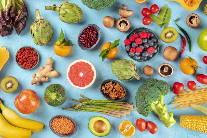 Vegan food. Healthy diet concept. Fruits, vegetables, pasta, nuts, legumes etc, Vegan food. Healthy diet concept. Fruits, vegetables, pasta, nuts, legumes, mushrooms, shot from above on a blue background. A flat lay composition
