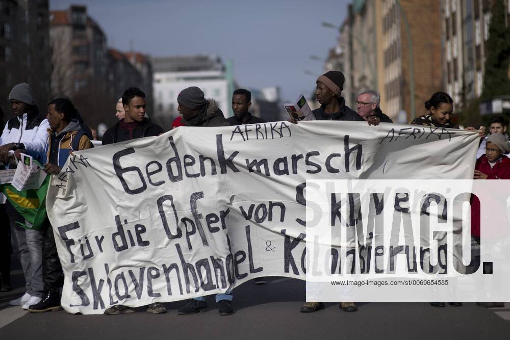 Gedenkmarsch Kolonialgeschichte DEU, Deutschland, Germany, Berlin, 27.02.2016 Demonstranten mit Transparent beim 10. Gedenkmarsch zur Erinnerung an die afrikanischen Opfer von Versklavung, Kolonialismus und rassistischer Gewalt vom Komitee fuer ein afrikanisches Denkmal in Berlin und afrikanischer Vereine in Berlin. Dieser Gedenkmarsch wurde ins Leben gerufen, um der Forderung nach Anerkennung der Verbrechen gegen Schwarze Menschen und Menschen afrikanischer Herkunft Nachdruck zu verleihen. Anlass ist die Berliner Afrika-Konferenz von 1884 - 1885, auf der Afrika vor 130 Jahren unter den europaeischen Kolonialmaechten aufgeteilt wurde. Mehr als 30 Millionen Afrikanerinnen und Afrikaner wurden Opfer von Versklavung und kolonialen Verbrechen gegen die Menschlichkeit. Die von Deutschland an den Herero und Nama begangenen Voelkermorde in Namibia und die Kriegsverbrechen in Tansania im Maji- M
