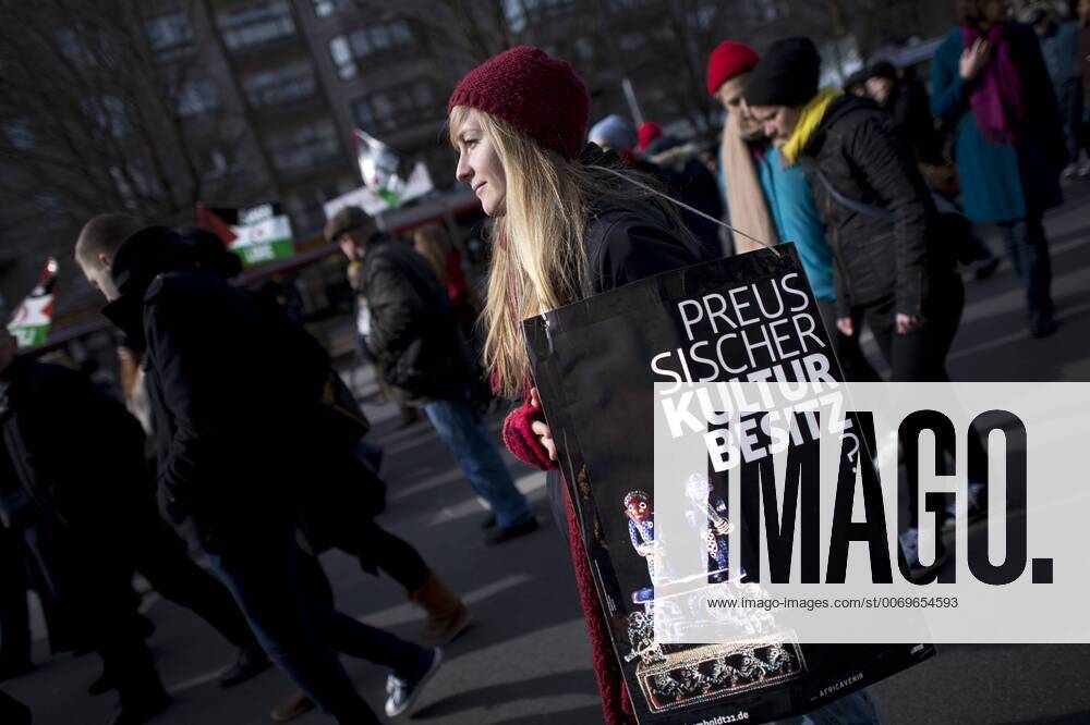 Gedenkmarsch Kolonialgeschichte DEU, Deutschland, Germany, Berlin, 27.02.2016 Demonstrant mit Plakat Preussischer Kulturbesitz gegen die Kolobialgeschichte und die Aneigung afrikanischer Kulturgueter durch deutsche Museen und dem Humboldt Forum beim 10. Gedenkmarsch zur Erinnerung an die afrikanischen Opfer von Versklavung, Kolonialismus und rassistischer Gewalt vom Komitee fuer ein afrikanisches Denkmal in Berlin und afrikanischer Vereine in Berlin. Dieser Gedenkmarsch wurde ins Leben gerufen, um der Forderung nach Anerkennung der Verbrechen gegen Schwarze Menschen und Menschen afrikanischer Herkunft Nachdruck zu verleihen. Anlass ist die Berliner Afrika-Konferenz von 1884 - 1885, auf der Afrika vor 130 Jahren unter den europaeischen Kolonialmaechten aufgeteilt wurde. Mehr als 30 Millionen Afrikanerinnen und Afrikaner wurden Opfer von Versklavung und kolonialen Verbrechen gegen die Mens