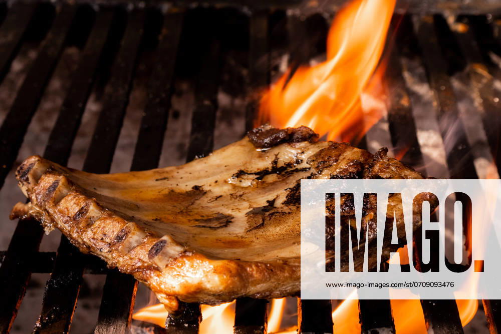 A succulent pork chop is expertly grilled over a fiery barbecue, capturing the essence of traditional Mexican home cooking. The flames lick the meat, enhancing its flavors. Model Released EduardoGavira_ID22276_651178_004