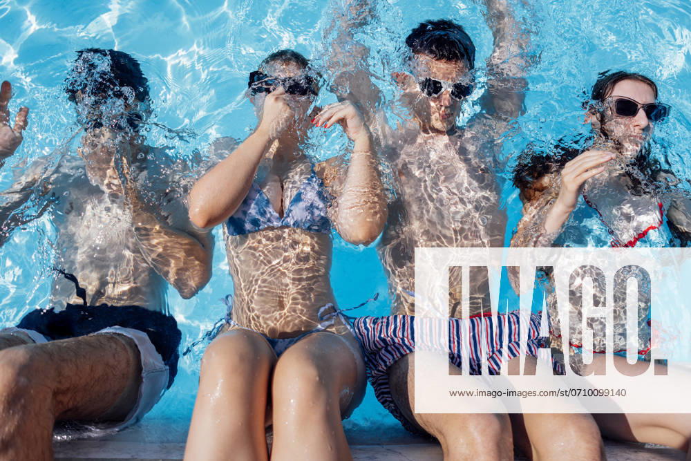 Cute teens in swimsuits and sunglasses in the pool. Smiling boys and girls dive into the clear water. Cute teens in swimsuits and sunglasses in the pool. Smiling boys and girls dive into the clear water. Joyful teenagers relax and have fun together. ,model released, Symbolfoto
