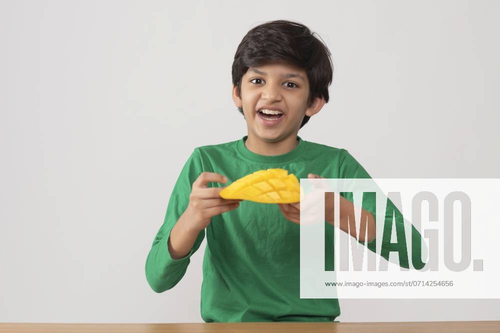 Portrait of happy boy holding a segmented slice of mango ,model released, Symbolfoto