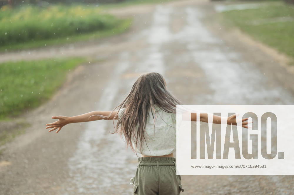 Long hair girl with arms outstretched standing and enjoying rain at back yard model released, Symbolfoto, ANAF03336