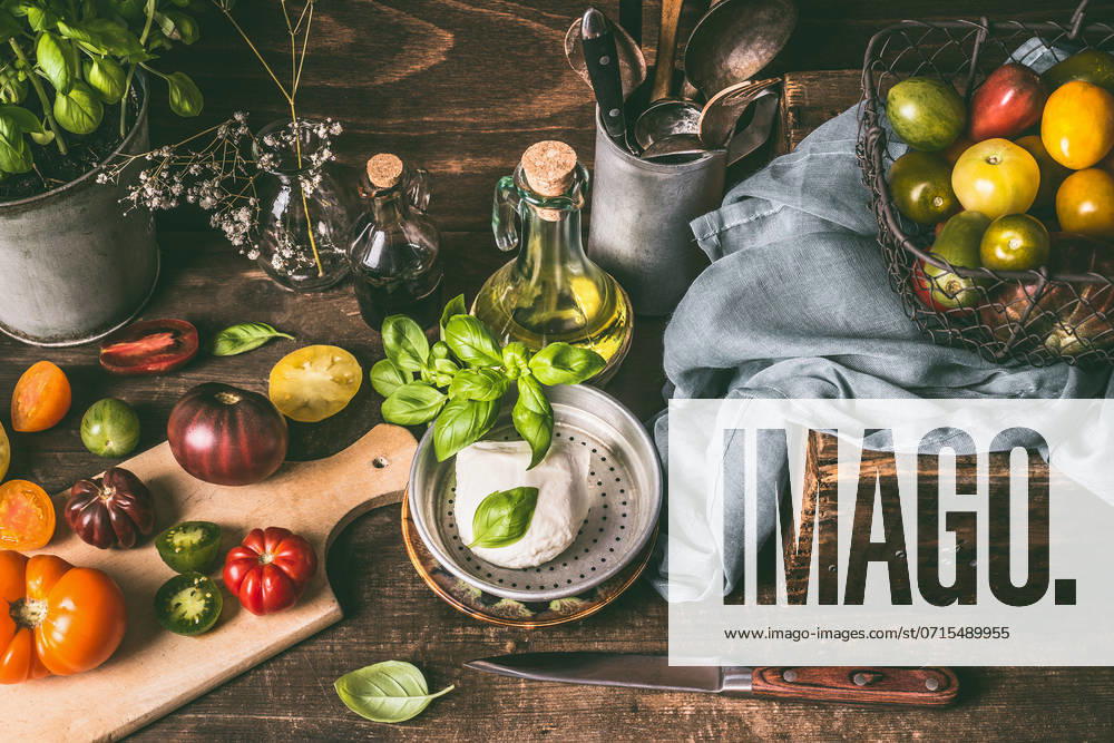 Mozzarella or burrata cheese , colorful tomatoes on dark rustic wooden kitchen table with , ingredients and cooking tools. Country style food background, still life, top view. ,model released, Symbolfoto