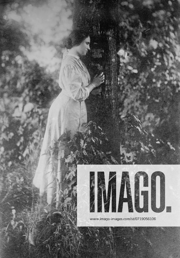 Helen Keller, standing next to tree, 1912.