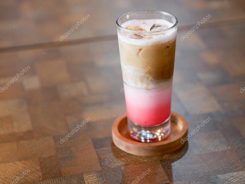 A glass of strawberry latte on a wooden table