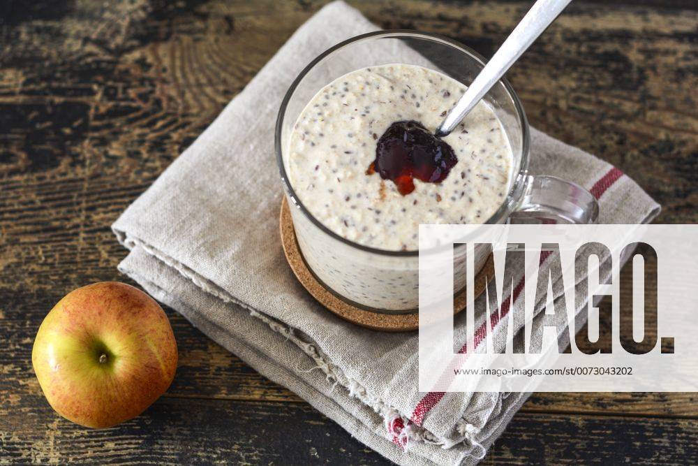 Glass of porridge with jam, linseed and chia seed and an apple on wood ODF001422