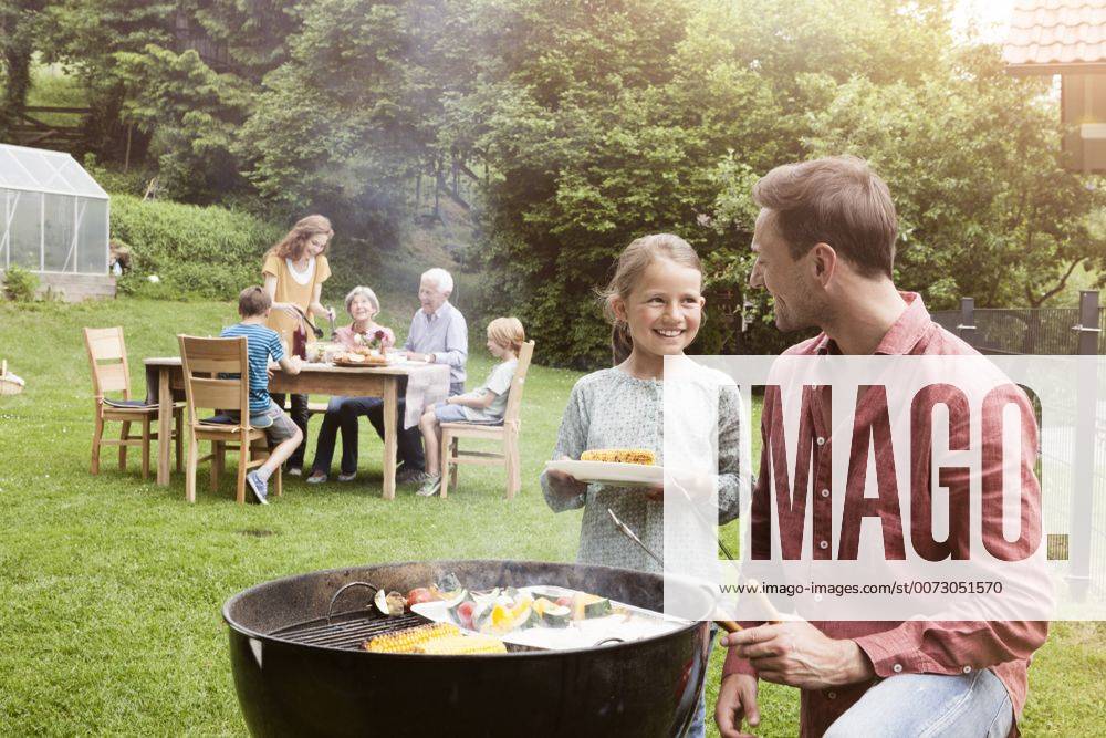 Grillen mit der Familie - Model Released Smiling father and daughter on a family barbecue model released Symbolfoto property released RBF004774