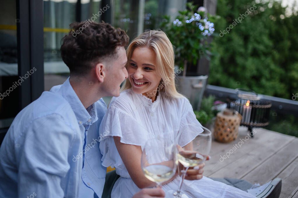 A young couple clinking with wine outdoors, weekend away in tiny house in countryside, sustainable living.