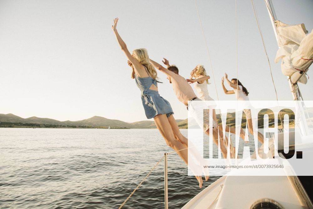 Symbolbilder Familie auf Segel-Trip Four people jumping off the side of a sail boat into a lake. Four people jumping off the side of a sail boat into a lake. 25342
