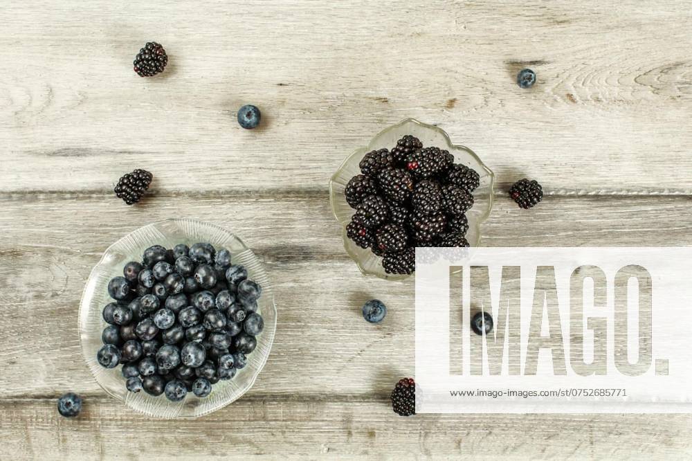 Top down view, small glass bowls with blueberries and blackberri, Top down view, small glass bowls with blueberries and blackberries some scattered on gray wood desk, Top down view, small glass bowls with blueberries and blackberries some scattered on gray wood desk, 27.11.2023,