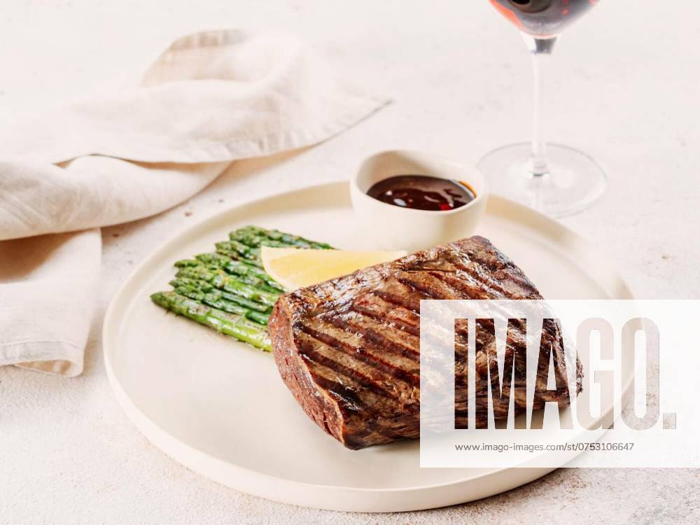 Grilled meat steak on plate with lemon and asparagus, Grilled meat steak on plate with lemon and asparagus on white table background. Food and cuisine concept. Restaurant-style plating, with red wine glass on table, Grilled meat steak on plate with lemon and asparagus on white table background. Food and cuisine concept. Restaurant-style plating, with red wine glass on table, 10.01.2024,