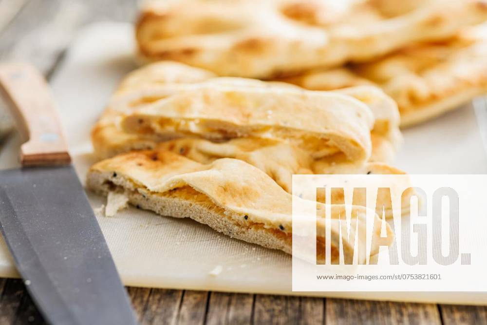 IMAGO Creative, Food, Brot, Naan Freshly Baked Naan Bread on cutting board on wooden table, Freshly Baked Naan Bread on cutting board on a wooden table, Freshly Baked Naan Bread on cutting board on a wooden table, 19.03.2024,