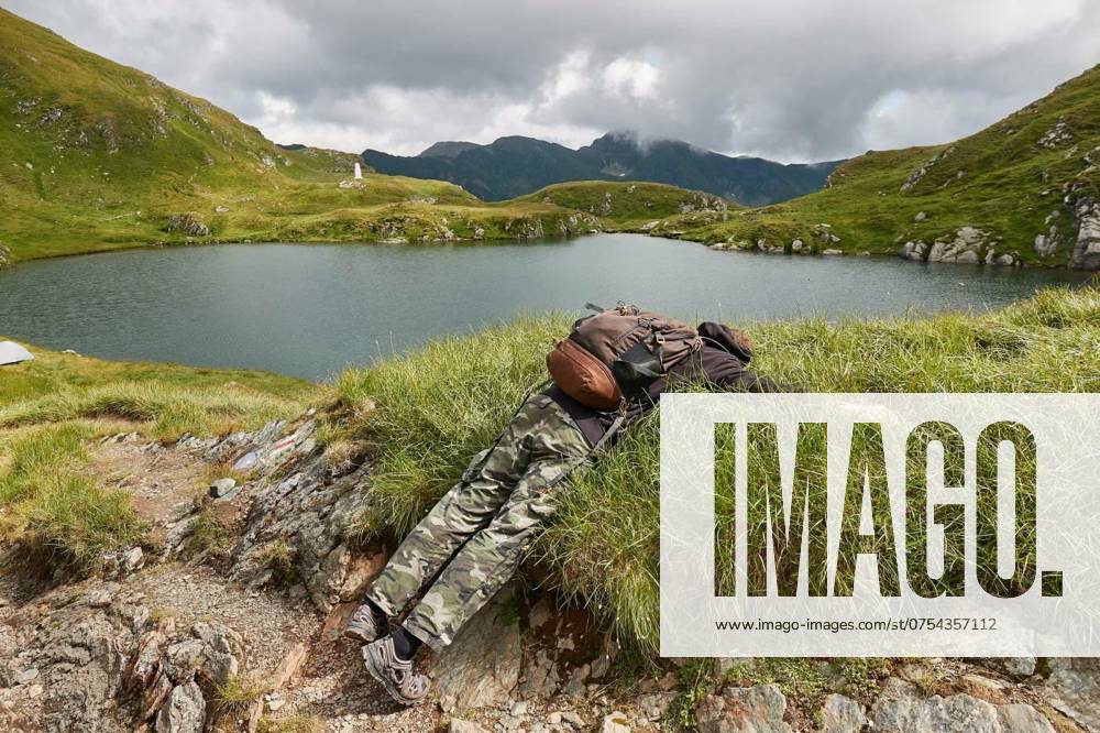 IMAGO Creative, Gesellschaft, Leisure Sickness Hiking in the Fagaras mountains, High mountain lake landscape with hiker laying down on the grass face down, High mountain lake landscape with hiker laying down on the grass face down model released, Symbolfoto , 24.05.2024,