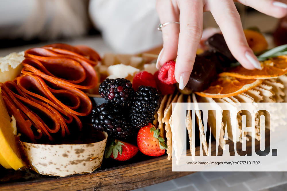 Woman s hand picking a raspberry off charcuterie grazing board San Diego, California, United States R_GPXONO24082198-1521260-01