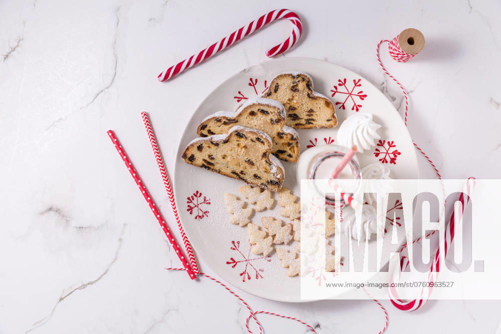 Flasche Milch mit traditionellem Christstollen, kleinen Keksen und Zuckerstangen auf weißem Hintergrund. Deutsches Weihnachtsbrot Bottle of milk with traditional Christmas stollen, small cookies and candy cane on white background. German Christmas bread