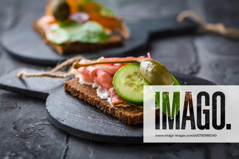 IMAGO Creative, Food, Brotzeit Offenes Sandwich mit Prosciutto auf Schwarzbrot (Pumpernickel) auf Schneidebrett Open sandwich with prosciutto on black bread (pumpernickel) on cutting board