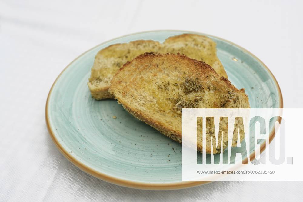 IMAGO Creative, Food, Brot, Knoblauchbrot Geröstetes Brot mit Olivenöl, Kräutern und Knoblauchsalz auf einem blauen Teller, Kopierraum, gewählter Fokus, geringe Schärfentiefe Toasted bread with olive oil, herbs and garlic salt on a blue plate, copy space, selected focus, narrow depth of field