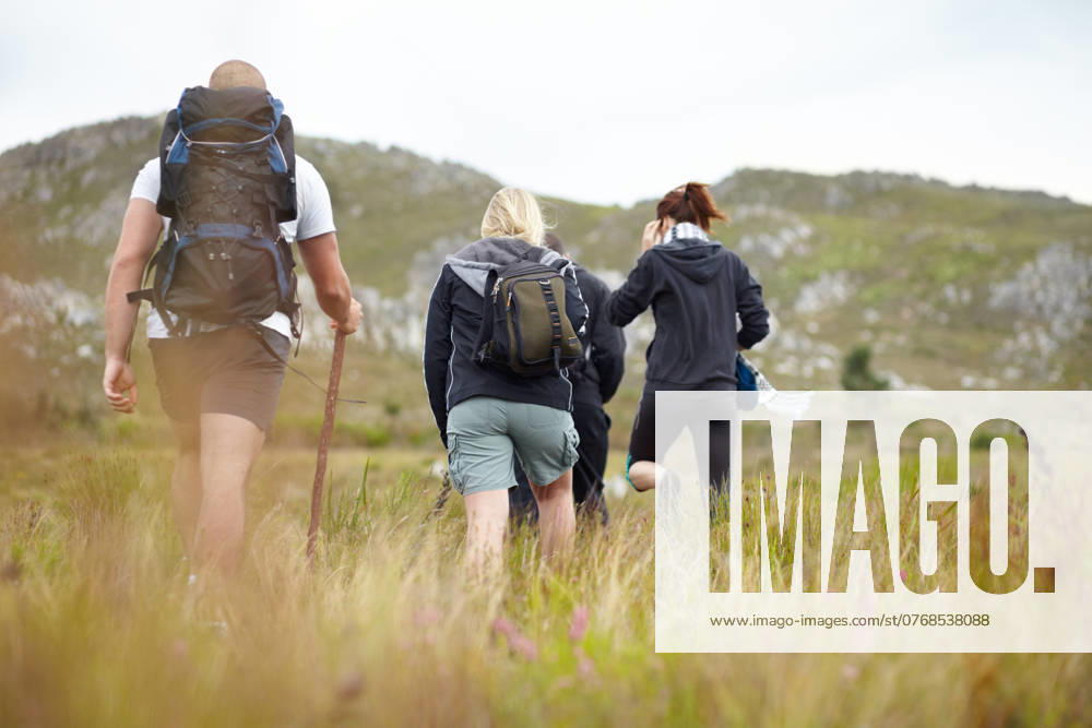 Nature, backpack and group of friends on hiking adventure in mountain with freedom from back. Travel, trekking and people walking in countryside, men and women on natural outdoor journey together model released property released