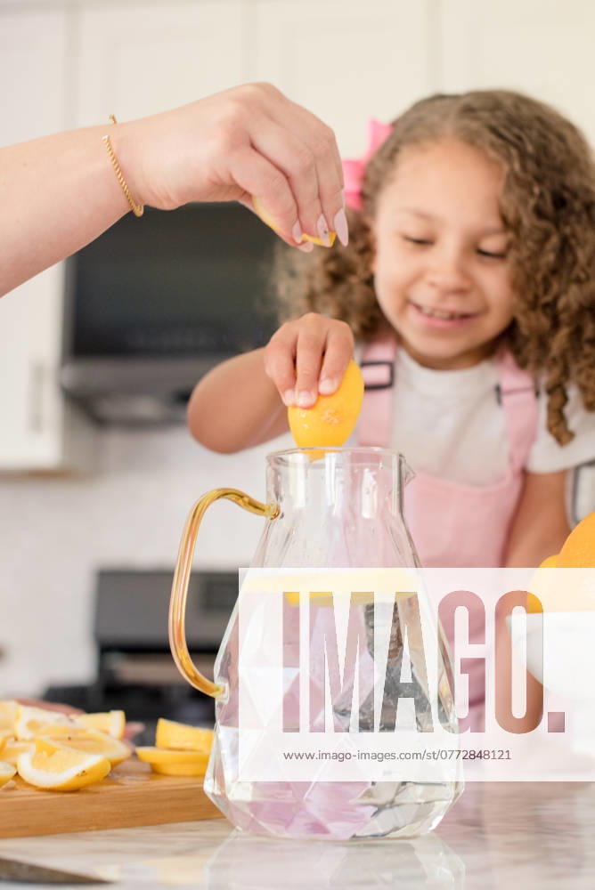Little girl and mom squeezing lemon slices into pitcher San Francisco, California, United States CR_HOOX240731-1501862-01 ,model released, Symbolfoto ,property released