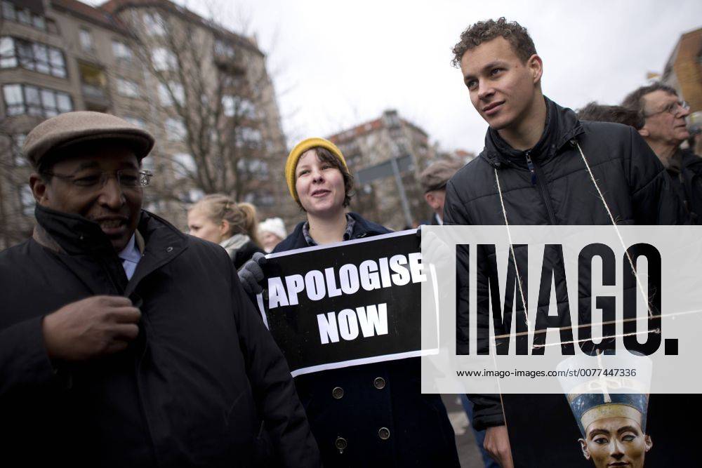 Gedenkmarsch Kolonialgeschichte DEU, Deutschland, Germany, Berlin, 25.02.2017 Demonstrant mit Plakat Freedom of Movement und Foto der Nofretete gegen die Kolobialgeschichte und die Aneigung afrikanischer Kulturgueter durch deutsche Museen und dem Humboldt Forum und Plakat Apologise now, Entschuldigung sofort, beim 11. Gedenkmarsch zur Erinnerung an die afrikanischen Opfer von Versklavung, Kolonialismus und rassistischer Gewalt vom Komitee fuer ein afrikanisches Denkmal in Berlin und afrikanischer Vereine in Berlin. Dieser Gedenkmarsch wurde ins Leben gerufen, um der Forderung nach Anerkennung der Verbrechen gegen Schwarze Menschen und Menschen afrikanischer Herkunft Nachdruck zu verleihen. Anlass ist die Berliner Afrika-Konferenz von 1884 - 1885, auf der Afrika vor 130 Jahren unter den europaeischen Kolonialmaechten aufgeteilt wurde. Mehr als 30 Millionen Afrikanerinnen und Afrikaner wur