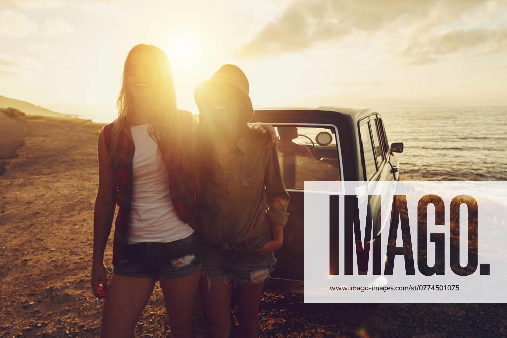 Sunset lens flare with women, car and road trip, travel with friends at beach, outdoor with nature and sea holiday. Transportation, freedom and sunshine on summer vacation, happiness with adventure. model released property released