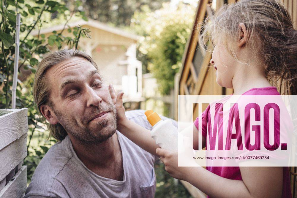 IMAGO Creative, Jahreszeit Sommer, Sonnenschutz Daughter applying sunscreen on father s face in garden model released Symbolfoto property released JOSF00585