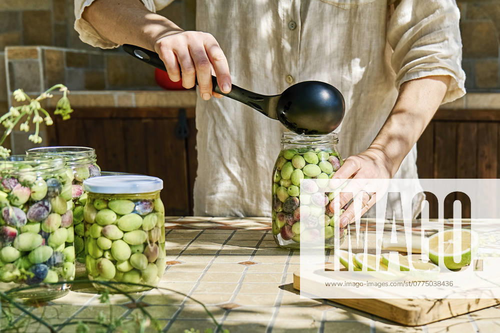 Mature woman preparing fermented olives in glass jar model released, Symbolfoto property released, CATF00449