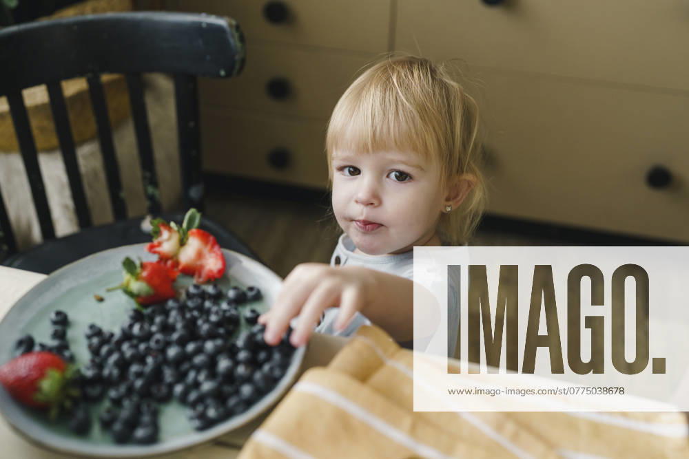 Girl having blueberries at table in kitchen model released, Symbolfoto property released, VBUF00594