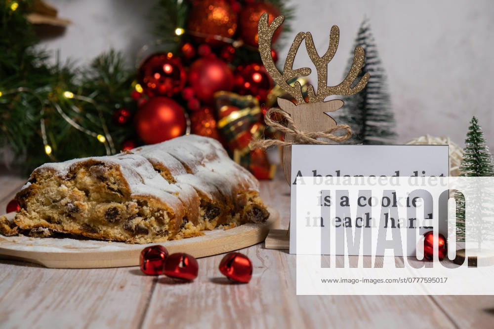 Greeting card with message A BALANCED DIET IS A COOKIE IN EACH HAND joke humor. Christmas Stollen in Christmas lights and decoration. Traditional sweet fruit loaf with icing sugar festive pastry dessert. Holiday baking food Greeting card with message A BALANCED DIET IS A COOKIE IN EACH HAND joke humor. Christmas Stollen in Christmas lights and decoration. Traditional sweet fruit loaf with icing sugar festive pastry dessert. Holiday baking food concept.