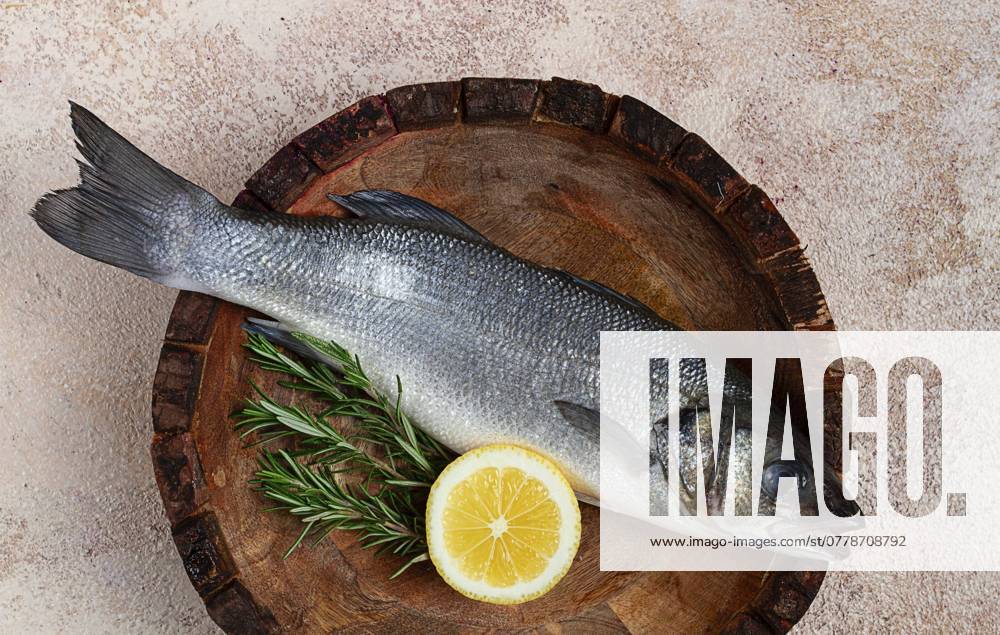 Frischer, roher Wolfsbarsch, in einer Holzplatte, Ansicht von oben, ohne Personen Fresh, raw sea bass fish, in a wooden plate, top view, no people