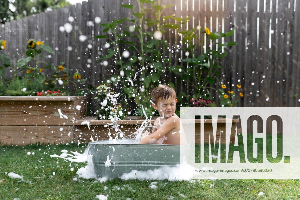 IMAGO Creative, Sommer, Sommertage im Garten Child splashes in a metal tub outdoors, surrounded by garden flowers. Norman, Oklahoma, United States CR_AOVS241111B-1577587-01 ,model released, Symbolfoto