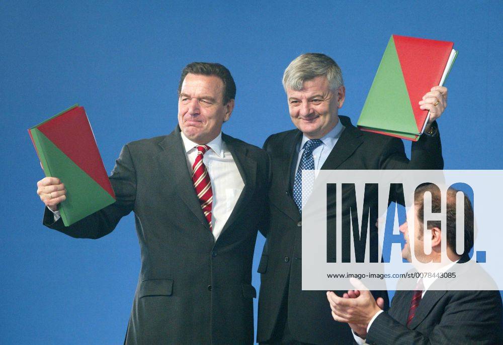 Unterschrift unter die Koalitionsvereinbarung zwischen SPD und Gruene : Bundeskanzler Gerhard Schroeder (l), SPD, und Bundesaussenminister Joschka Fischer, Gruene, umarmen sich. Es applaudiert Olaf Scholz, designierter SPD Generalsekretaer. Berlin, 16.10.2002, Berlin Deutschland
