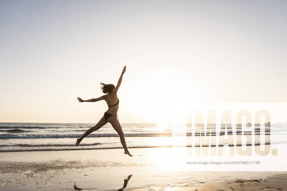 Young woman jumping for joy on the beach model released, Symbolfoto, UUF15143