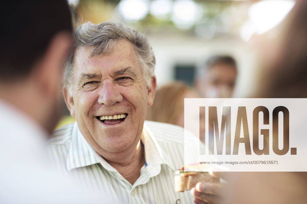 Happy senior man socializing on a garden party model released Symbolfoto property released ZEF13981