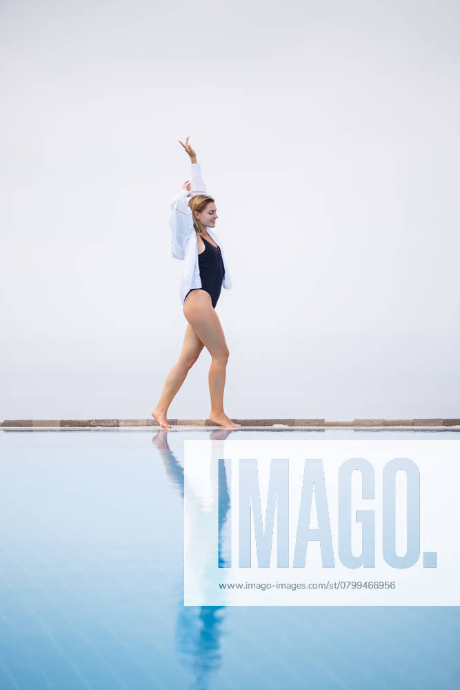 An attractive young woman in a black swimsuit and white shirt stands near the pool with a panoramic view., model released, , 49143094.jpg, woman, beach, fashion, spa, water, person, girl, sport, fitness, erotic, vintage, summer, nature, face, sun, bikini, pool, swimming, view, swimsuit, female, young, people, swimwear, vacation, travel, luxury, relaxation, resort, leisure, one, indoors, sunbathing, rest, fashionable, sexy, recreation, villa, lifestyle, body, fun, hotel, slim, tropical, day, bali, pretty, style, outdoor, outdoors RECORD DATE NOT STATED