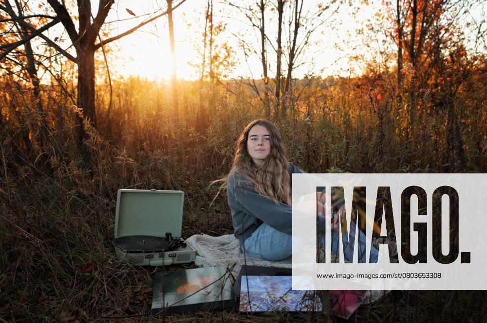 IMAGO Creative, Jahreszeit Sommer, Sommerferien Gorgeous teen girl listening to record player in sunny field Wooster, Ohio, United States CR_JOKU250217-1644783-01 ,model released, Symbolfoto
